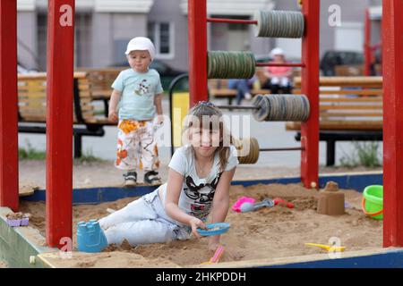 La fille joue dans le bac à sable à l'aire de jeux Banque D'Images