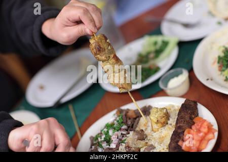 L'homme tient une brochette de kebab dans le restaurant libyen Banque D'Images