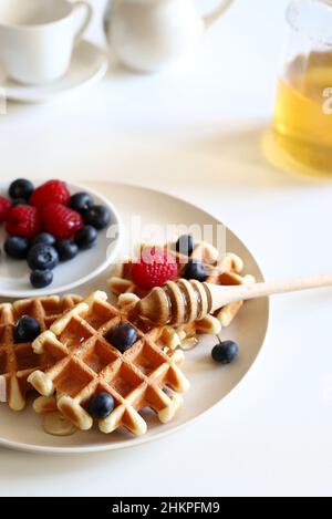 Gaufres belges avec fruits frais et miel sur une assiette isolée sur fond blanc.Directement au-dessus. Banque D'Images
