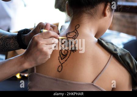 SABAH, MALAISIE - 30 MAI, 2019: Une artiste féminine de henné applique un motif de henné sur le ventre à Kota Kinabalu, Sabah en Malaisie. Banque D'Images