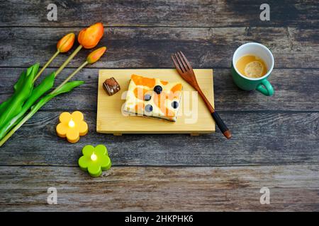 Le temps du café en Allemagne : gâteau au fromage maison et un café sur une table en bois avec des fleurs de tulipe orange pour la décoration. Banque D'Images