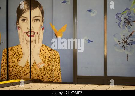 Stuttgart, Allemagne - 31 décembre 2021 : image d'une femme sur la vitrine de la ville.Un jeune tient les mains face au visage par surprise. Banque D'Images