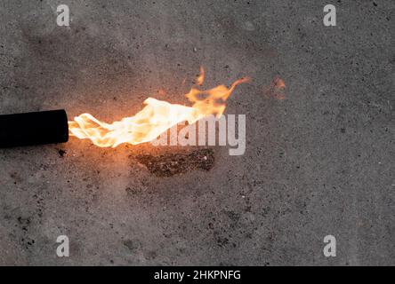 Longue flamme d'un brûleur à gaz sur fond de béton gris Banque D'Images