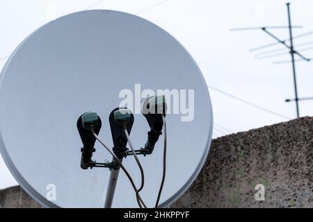 Jeu de convertisseurs satellite sur fond flou de toit et de vaisselle de réception blanche Banque D'Images