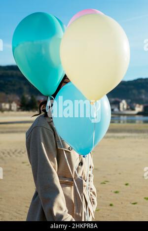 Jeune femme couvrant son visage avec des ballons Banque D'Images