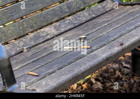 Le banc de stationnement avec des cigarettes et des bouchons de bouteille laissés sur les sièges mauvaises habitudes problèmes de santé et de terrer butin une aire de repos pour les personnes plus attentionnés Banque D'Images