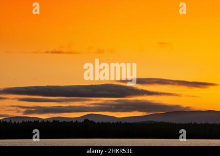 Le soleil se couche derrière les collines au-dessus du Loch Morlich dans les Highlands d'Écosse Banque D'Images