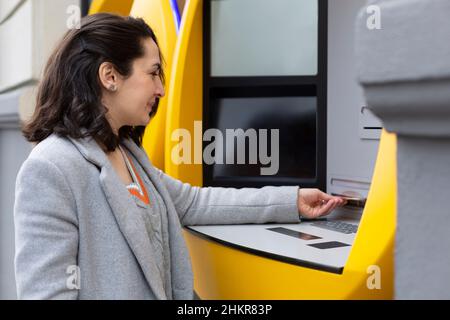 Femme élégante qui retire de l'argent à un distributeur automatique de billets.Espace pour le texte. Banque D'Images