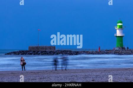 05 février 2022, Mecklembourg-Poméranie occidentale, Warnemünde : le phare de l'une des jetées à l'entrée du canal maritime de Rostock clignote dans la soirée.Le temps sec et froid de l'hiver attire encore les vacanciers et les visiteurs de jour à la plage même après le coucher du soleil, malgré le vent féroce.Photo: Jens Büttner/dpa-Zentralbild/dpa Banque D'Images