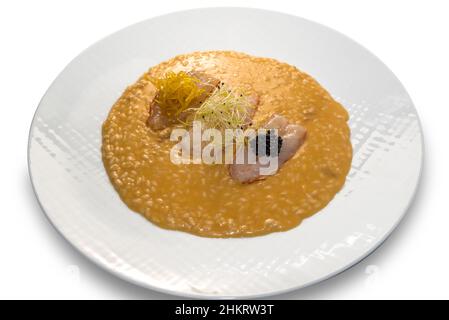 Risotto aux langoustines crues avec pousses, zeste de citron caramélisé et caviar.Dans un plat blanc isolé sur blanc Banque D'Images