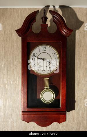 Maison brun mur horloge avec un pendule sur un mur léger. Banque D'Images