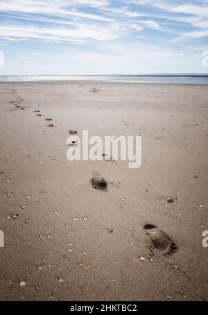 Quelques traces d'une empreinte humaine sur le sable d'une immense plage, avec la mer en arrière-plan et un ciel bleu avec quelques nuages, Isla Canela, Espagne Banque D'Images
