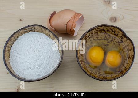 Cuire des œufs avec de la farine dans un bol de noix de coco. Banque D'Images