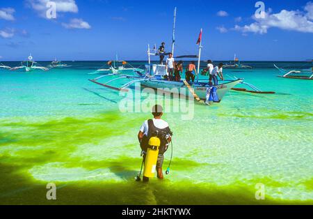 Des marins et des plongeurs préparent un bateau philippin traditionnel à outrigger amarré à White Beach sur l'île de Boracay, dans la région des Visayas occidentales aux Philippines. Banque D'Images