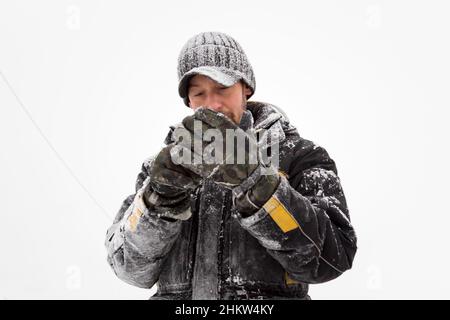 Le monteur dans une veste et une casquette noire avec visière met des gants Banque D'Images