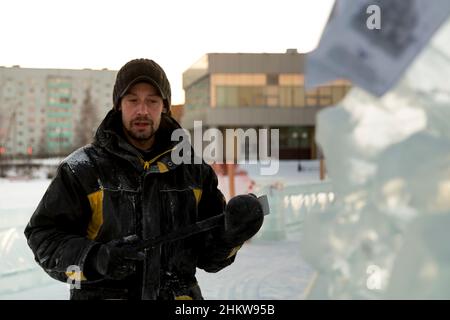 Portrait d'un assembleur de travail dans une veste d'hiver et d'un capuchon noir avec une visière près de la glace Banque D'Images