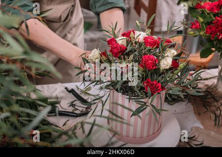 Le fleuriste fait des bouquets cadeaux dans des boîtes à chapeaux. Les mains féminines gracieuses font un beau bouquet. Lieu de travail du fleuriste. Concept de petite entreprise. Vue avant. Fleur Banque D'Images