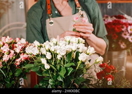 Bouquets-cadeaux à la fleuriste.Les mains féminines gracieuses font un beau bouquet.Lieu de travail du fleuriste.Concept de petite entreprise.Fleurs et accessoires.Mains Banque D'Images