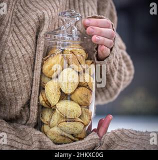 Pot en verre avec biscuits noix et lait condensé dans les mains des femmes. Banque D'Images