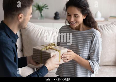 Petit ami aimant félicitant petite amie souriante, donnant boîte cadeau Banque D'Images