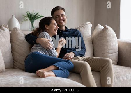 Couple riant s'embrassant, se reposant sur un canapé ensemble Banque D'Images