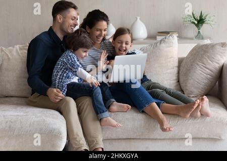 Parents heureux avec deux enfants qui passent des appels vidéo ensemble Banque D'Images