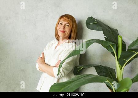 Jolie femme d'âge moyen sur fond gris dans un chemisier blanc. Banque D'Images