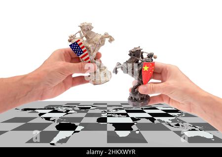 Guerre commerciale entre les Etats-Unis et la Chine. Les mains détiennent deux pièces d'échecs d'un cheval, avec des drapeaux américains et chinois les plaçant sur un échiquier avec une carte du monde Banque D'Images