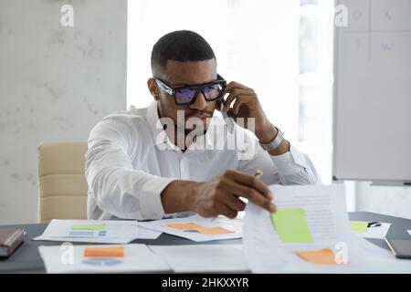 Un jeune homme d'affaires africain concentré travaillant avec la mêlée a arrangé des papiers adhésifs Banque D'Images
