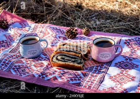 Délicieux strudel aux graines de pavot et deux tasses de café sur une serviette par temps ensoleillé. Banque D'Images
