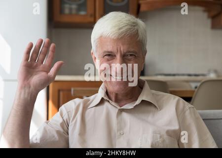 Joyeux homme âgé de 60s ans souriant à l'appareil photo, en signe de main bonjour Banque D'Images