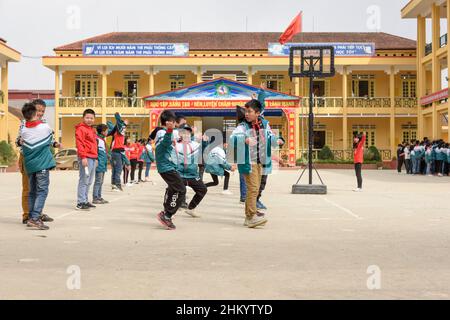 Les écoliers vietnamiens effectuent des exercices matinaux avec leur enseignant dans la cour d'école de Sapa (sa Pa), province Lao Cai, Vietnam, Asie du Sud-est Banque D'Images