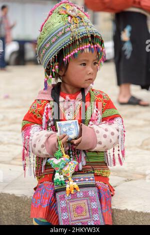 Une jeune fille, portant des vêtements traditionnels de la tribu Hmong, recueille de l'argent pour poser pour des photos par des touristes à Sapa (sa Pa), Lao Cai, Vietnam Banque D'Images