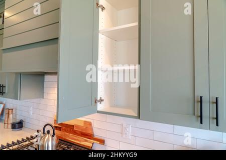Armoire murale de cuisine avec porte ouverte et étagères vides contre fond blanc.La table de cuisson, les appareils de cuisson et les outils de cuisine peuvent être vus sur le pays Banque D'Images