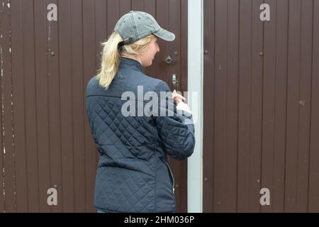 La fille verrouille la porte sur le poste.Fermeture du château.Une femme dans un chapeau près de la porte de la maison. Banque D'Images