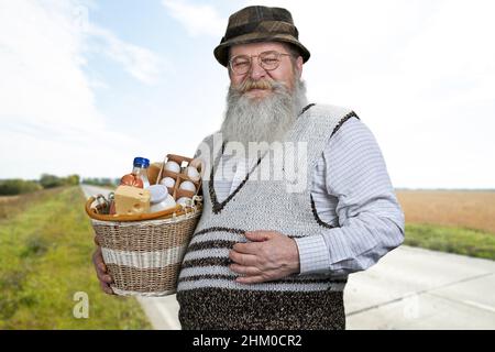 Travailleur agricole ou agriculteur détenant des produits frais avec vue sur le paysage rural.Agriculteur principal avec des champs agricoles verts en arrière-plan. Banque D'Images