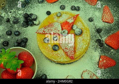 Petit déjeuner d'été sain, crêpes américaines classiques faites maison avec baies fraîches et sucre glace.Bleuets et fraises sur crêpes.Noir Banque D'Images