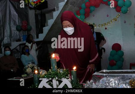 Une grand-mère musulmane tout en éclairant les bougies de Noël. Banque D'Images