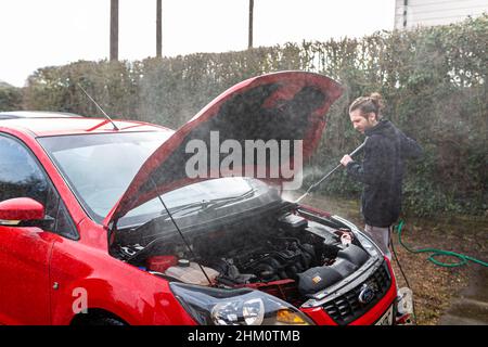 Woodbridge, Suffolk, Royaume-Uni février 24 2021: Un jeune homme à pression lave sa voiture propre Banque D'Images