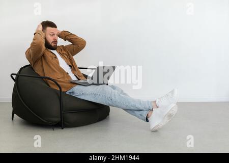 Homme freelance regardant un ordinateur portable dans Shock toucher Head à l'intérieur Banque D'Images