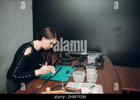 Tanner femme faisant des marchandises de ceinture de harnais en cuir sur l'atelier.Processus de travail de l'artisan du cuir. Banque D'Images