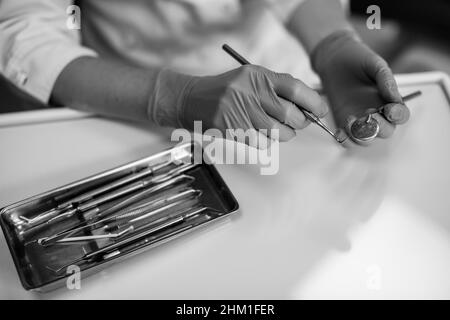Mains dentiste femelle avec instruments dentaires gros plan.Photo en noir et blanc. Banque D'Images