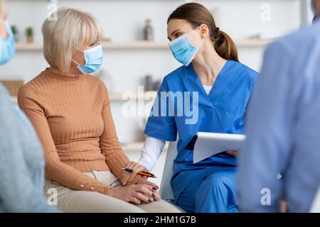 Femme âgée qui obtient l'appui d'une travailleuse de maison de soins infirmiers Banque D'Images