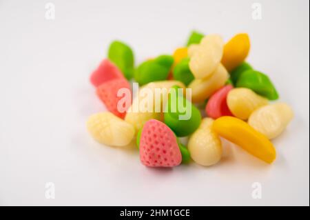 Gros plan d'une pile de bonbons en gelée colorés sous forme de fruits sur un fond blanc isolé. Banque D'Images