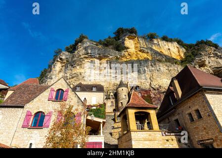 Falaise de calcaire et maisons historiques en pierres jaunes de la Roque-Gageac, Périgord, prises pendant un après-midi d'automne ensoleillé Banque D'Images