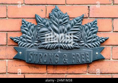 Saint John, N.-B., Canada - le 26 novembre 2017 : logo en métal sur le côté d'un bâtiment en briques avec les mots « STRONG & FREE » sous les feuilles d'érable. Banque D'Images