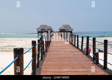 Jetée en bois et toits de chaume sur une plage tropicale, île de Zanzibar. Banque D'Images