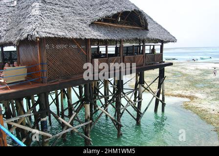 Jetée en bois et toits de chaume sur une plage tropicale, île de Zanzibar. Banque D'Images