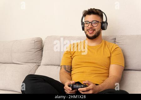 jeune homme tenant une manette jouant à des jeux vidéo avec son casque allumé Banque D'Images