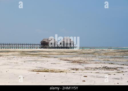 Jetée en bois et toits de chaume sur une plage tropicale, île de Zanzibar. Banque D'Images